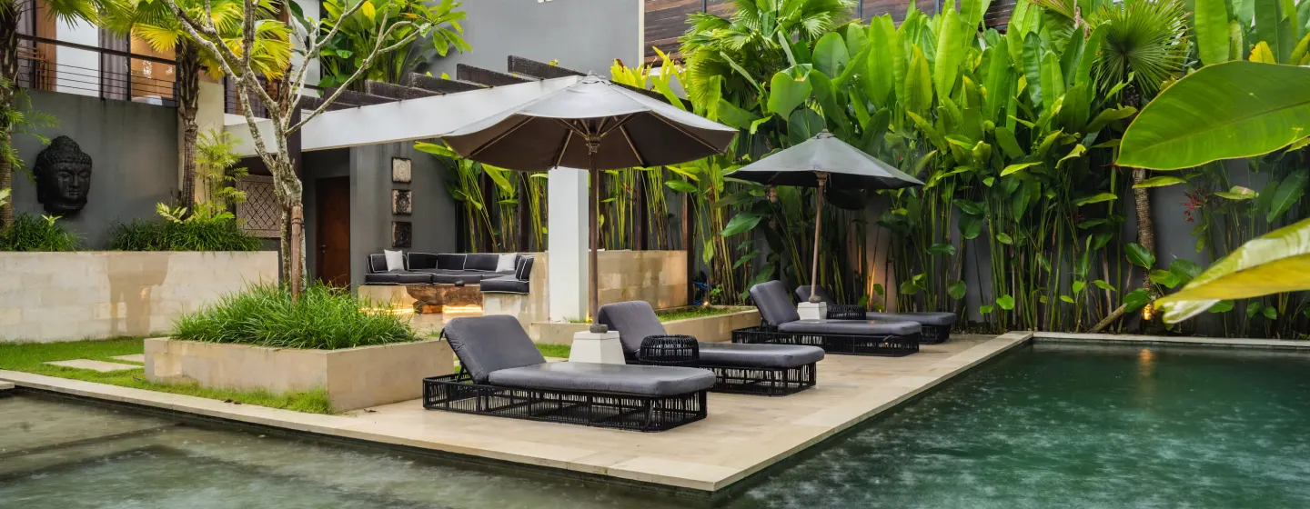 Kolam renang villa dengan kursi berjemur dan taman tropis